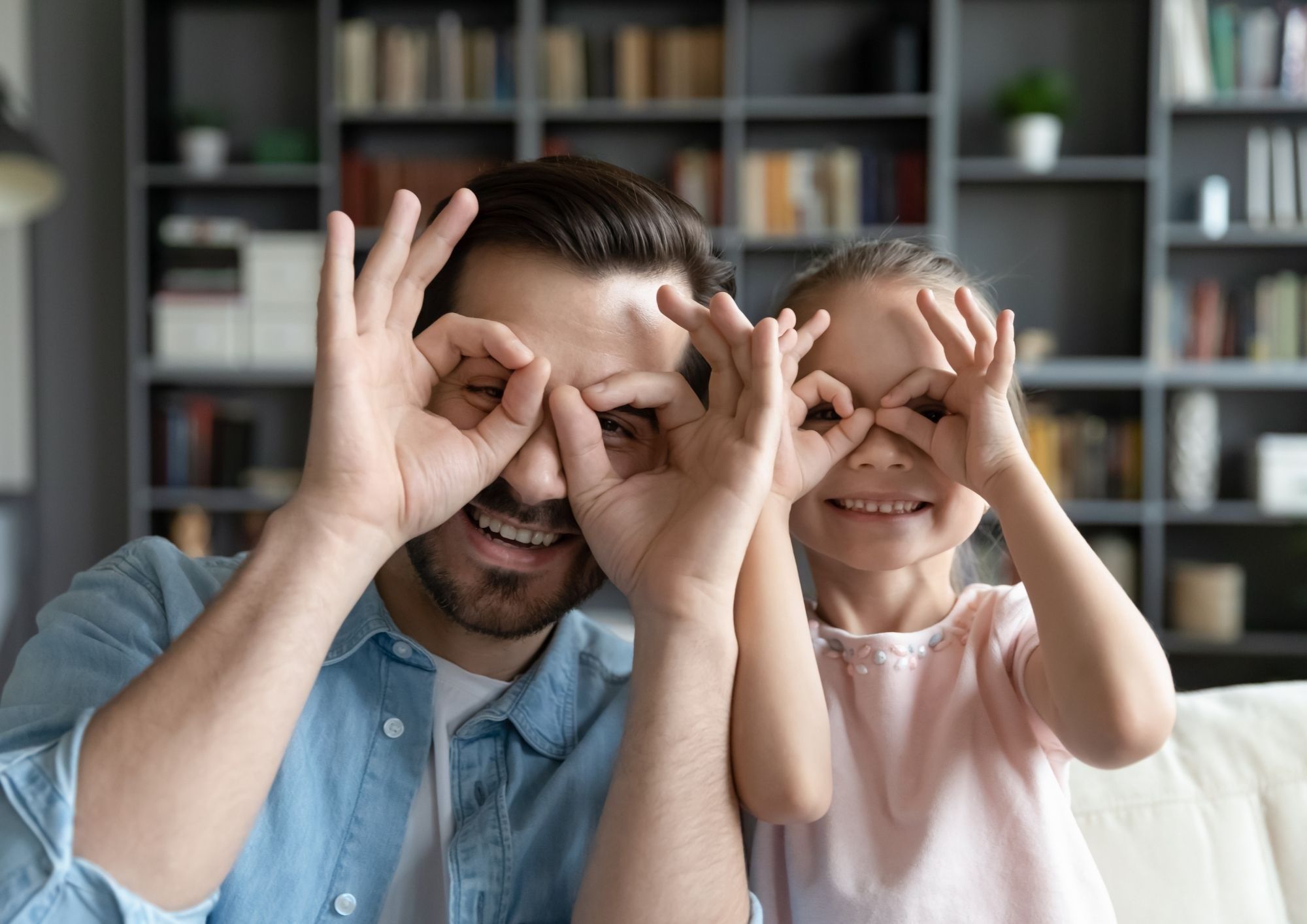 un papa et sa fille faisant des lunettes avec leurs mains